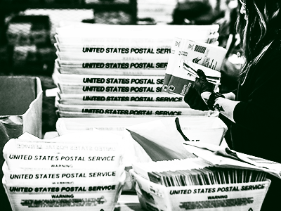 person holding ballots with postal boxes