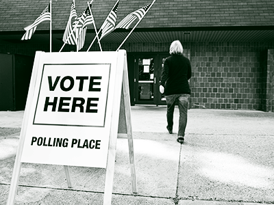 vote here sign in front of building with person walking in